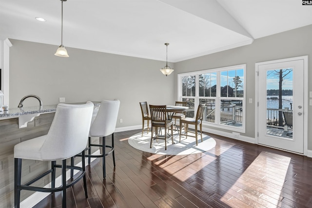 dining space featuring vaulted ceiling and a water view