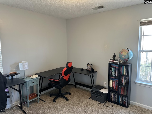 carpeted home office featuring a textured ceiling