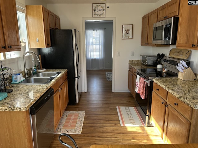 kitchen featuring light stone counters, appliances with stainless steel finishes, sink, and light hardwood / wood-style flooring