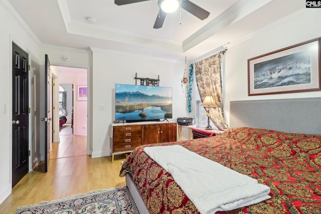 bedroom with a raised ceiling, crown molding, ceiling fan, and light hardwood / wood-style floors