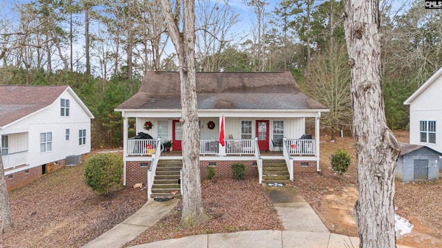 bungalow-style house with a porch, a storage unit, and central AC unit