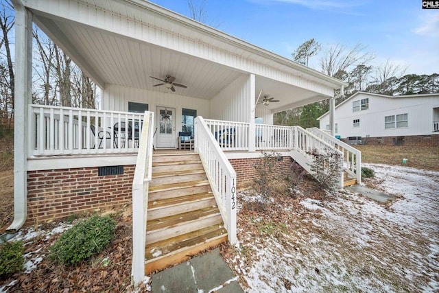 snow covered property entrance featuring covered porch and ceiling fan