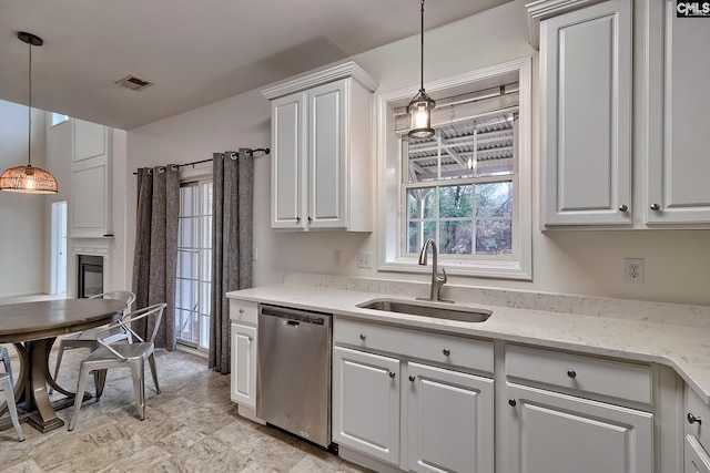 kitchen featuring white cabinetry, stainless steel dishwasher, sink, and pendant lighting