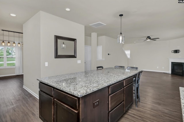 kitchen featuring a kitchen island, a breakfast bar, dark hardwood / wood-style floors, and decorative light fixtures