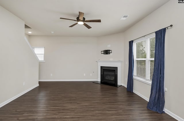 unfurnished living room featuring dark wood-type flooring and ceiling fan