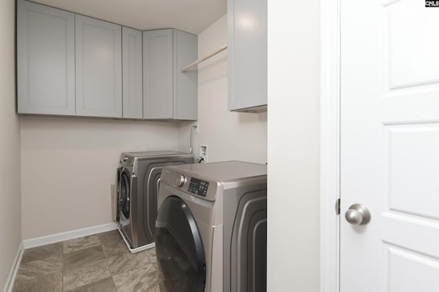 clothes washing area featuring washer and clothes dryer and cabinets