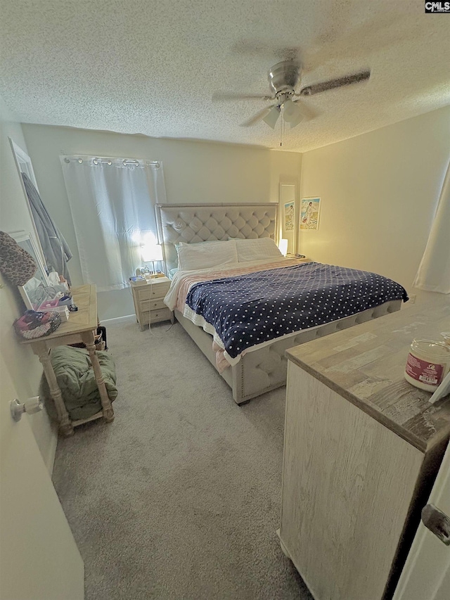 bedroom featuring ceiling fan, carpet floors, and a textured ceiling