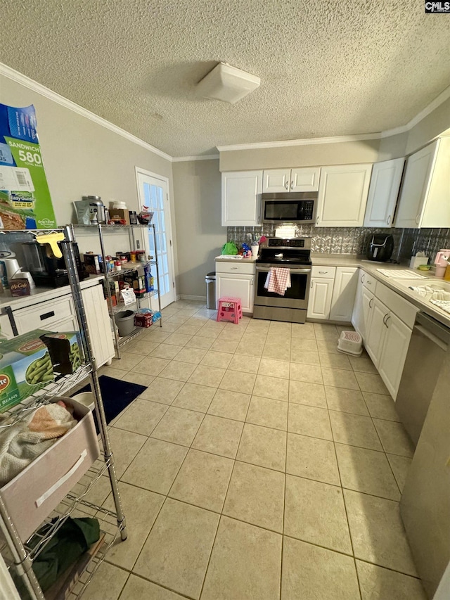 kitchen featuring stainless steel appliances, white cabinetry, light tile patterned flooring, and crown molding