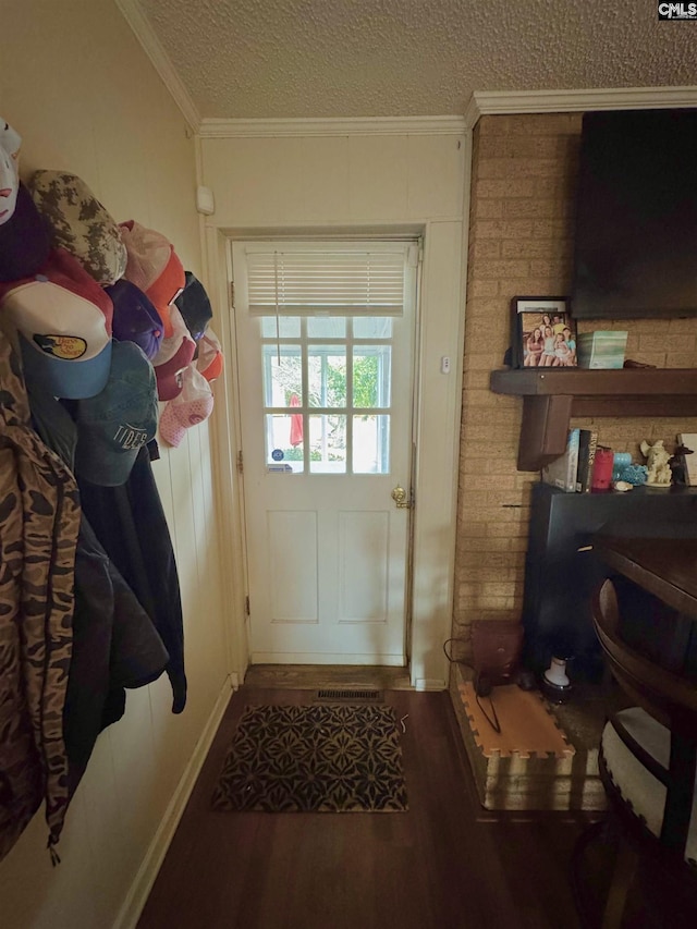 doorway featuring dark hardwood / wood-style flooring, ornamental molding, and a textured ceiling