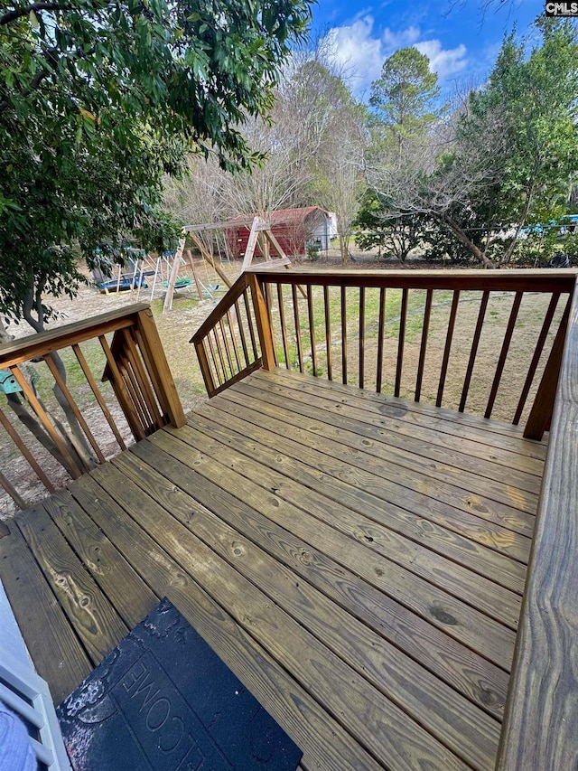 wooden terrace featuring a playground and a lawn