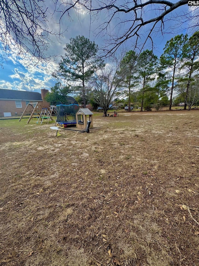 view of yard featuring a trampoline and a playground