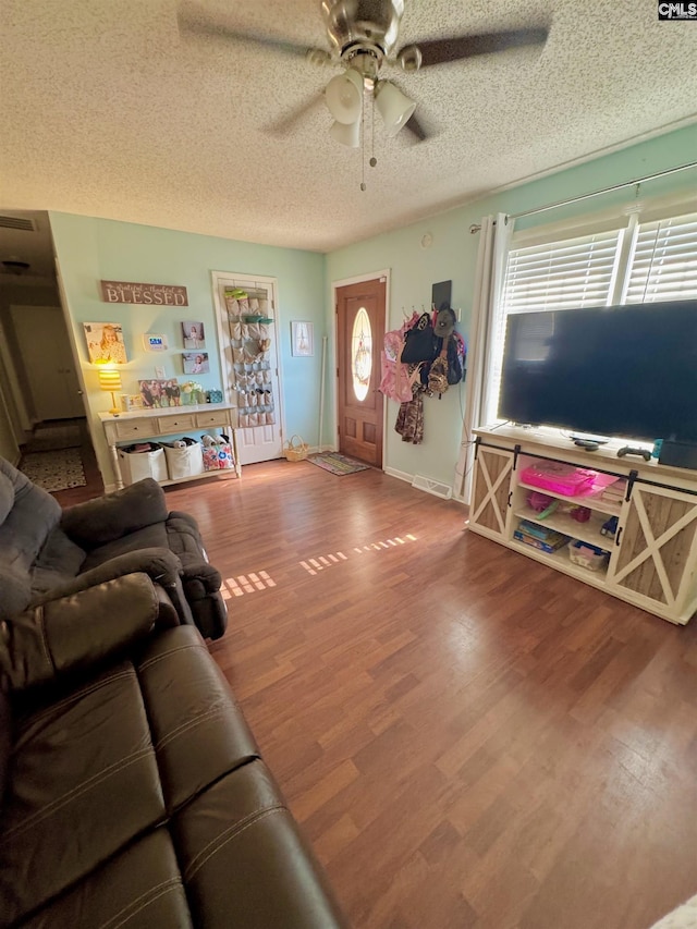 living room featuring ceiling fan, hardwood / wood-style flooring, and a textured ceiling