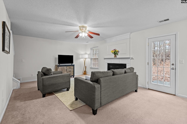 carpeted living room with ceiling fan, plenty of natural light, and a textured ceiling