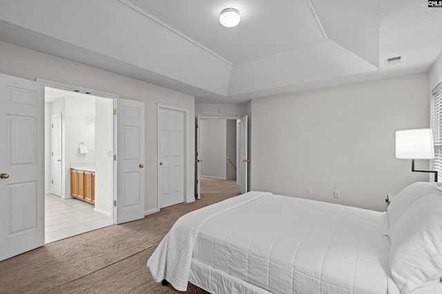 carpeted bedroom featuring connected bathroom and a tray ceiling