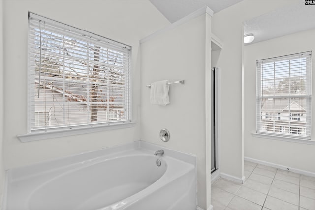 bathroom featuring plenty of natural light, a washtub, tile patterned floors, and a textured ceiling