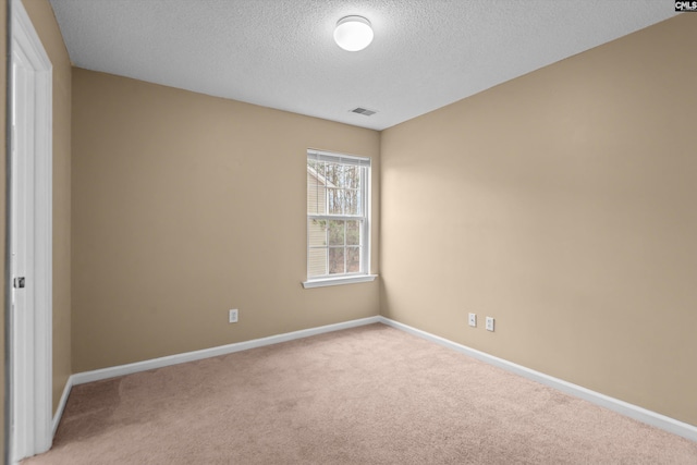 unfurnished room featuring light colored carpet and a textured ceiling