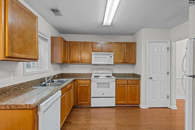 kitchen with sink, white appliances, a textured ceiling, and light wood-type flooring