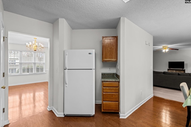 kitchen featuring white refrigerator, ceiling fan with notable chandelier, hardwood / wood-style floors, and a textured ceiling