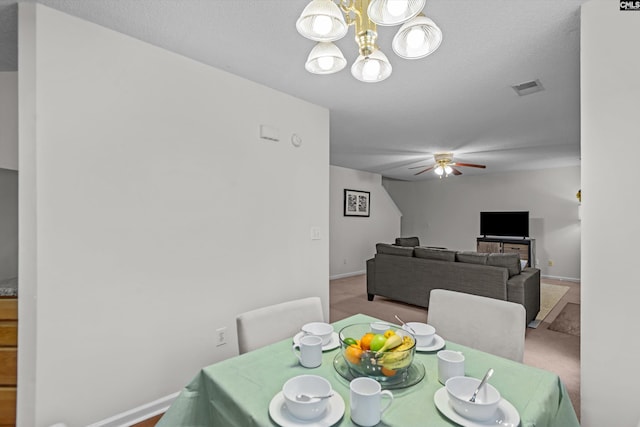 dining area featuring ceiling fan with notable chandelier, light carpet, and a textured ceiling