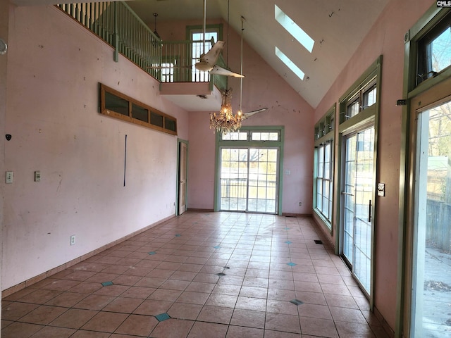 tiled spare room featuring an inviting chandelier, a skylight, and high vaulted ceiling