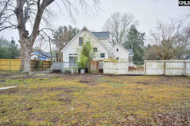 rear view of house with a wooden deck and a lawn