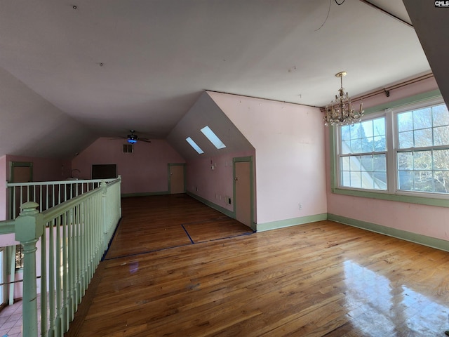 bonus room with lofted ceiling, hardwood / wood-style floors, and a notable chandelier