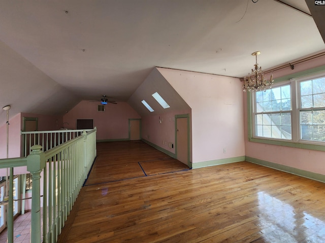 additional living space with vaulted ceiling, a chandelier, and light wood-type flooring