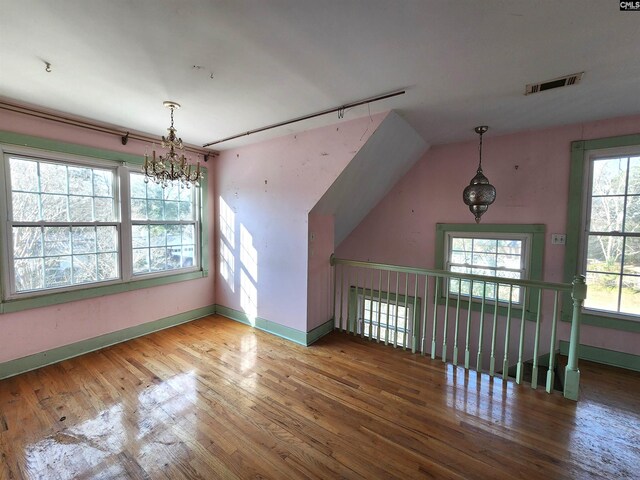 bonus room featuring hardwood / wood-style flooring and an inviting chandelier