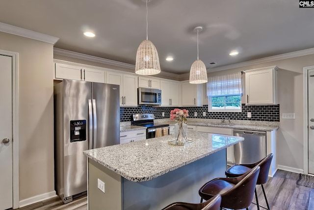 kitchen featuring white cabinetry, stainless steel appliances, a center island, and hanging light fixtures