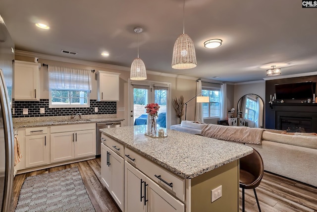 kitchen featuring white cabinetry, a kitchen breakfast bar, wood-type flooring, decorative backsplash, and decorative light fixtures