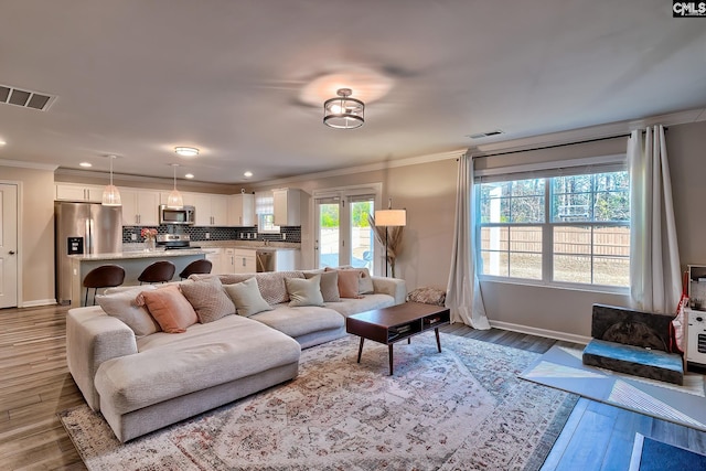 living room with crown molding, a healthy amount of sunlight, and hardwood / wood-style floors