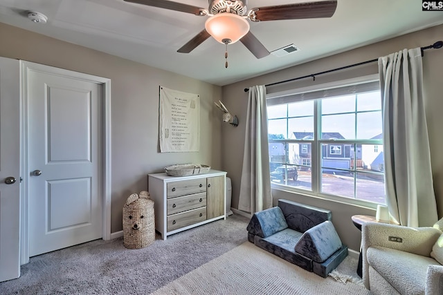 living area featuring light colored carpet and ceiling fan