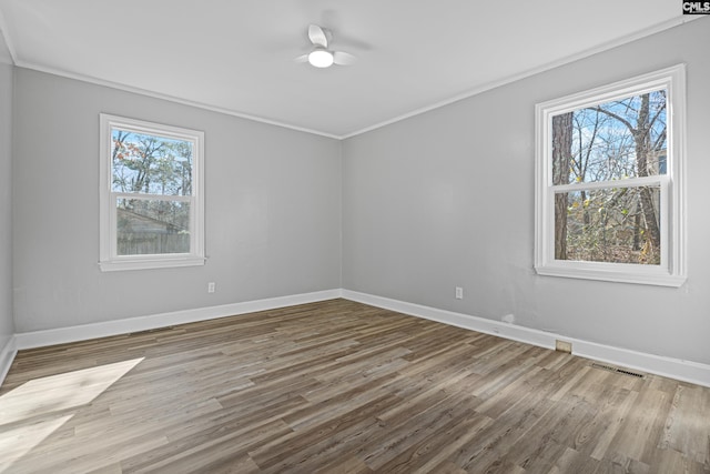 unfurnished room featuring crown molding, plenty of natural light, and hardwood / wood-style flooring