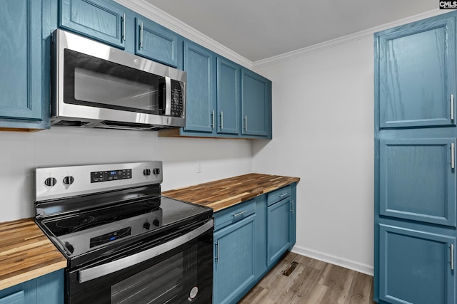 kitchen featuring stainless steel appliances, crown molding, blue cabinets, and butcher block countertops