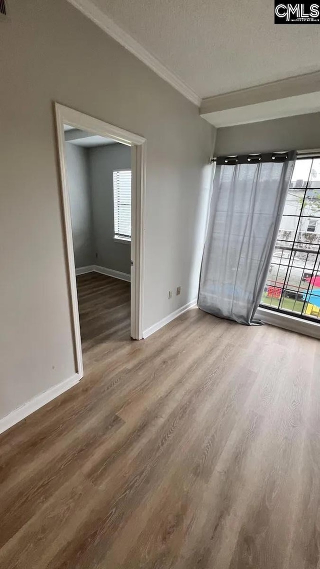 spare room featuring hardwood / wood-style flooring, crown molding, plenty of natural light, and a textured ceiling