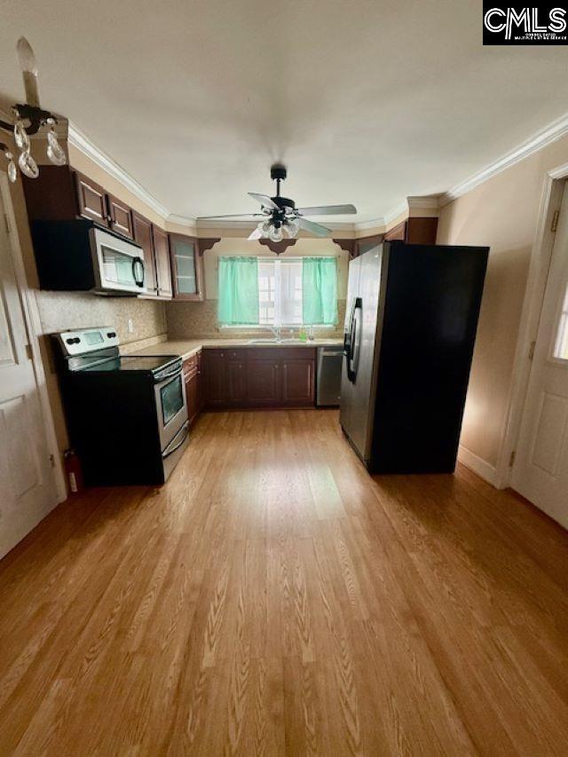 kitchen with sink, dark brown cabinets, light wood-type flooring, ornamental molding, and stainless steel appliances