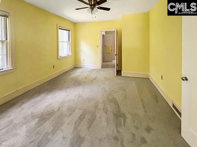 carpeted empty room with a wealth of natural light and ceiling fan