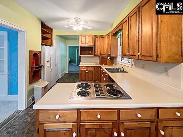 kitchen featuring white refrigerator with ice dispenser, stainless steel gas cooktop, sink, and ceiling fan