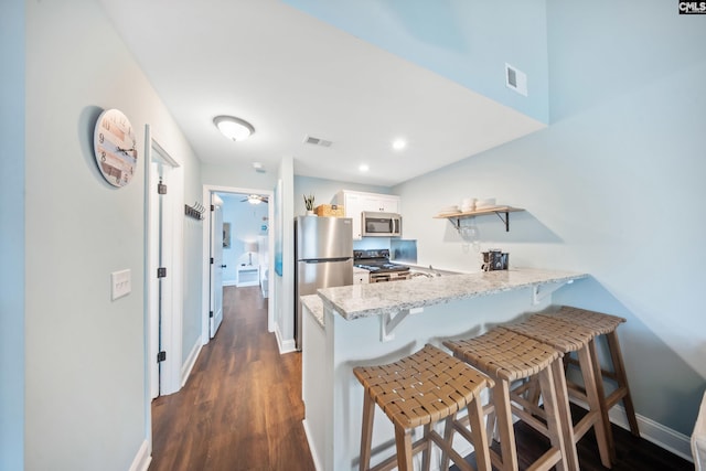 kitchen featuring white cabinetry, appliances with stainless steel finishes, kitchen peninsula, and a breakfast bar area