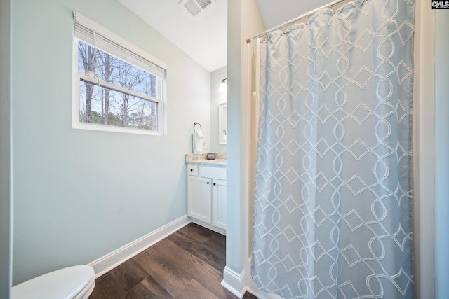 bathroom with vaulted ceiling, curtained shower, wood-type flooring, vanity, and toilet