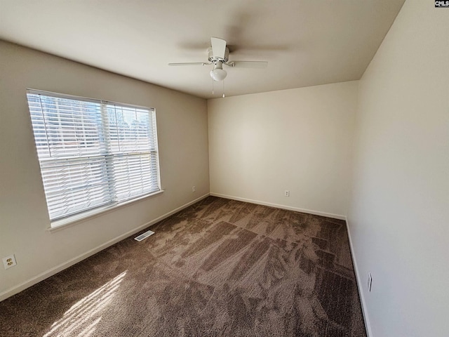 spare room with dark colored carpet and ceiling fan