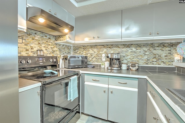 kitchen with black range with electric cooktop, decorative backsplash, stainless steel fridge, and extractor fan