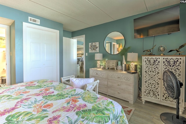 bedroom featuring a closet, ensuite bathroom, and light hardwood / wood-style flooring