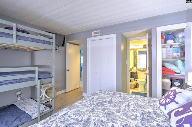 bedroom featuring ensuite bath, wood-type flooring, and a closet