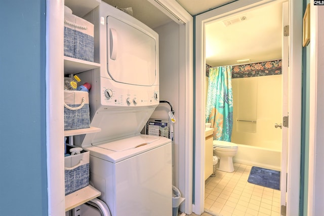 laundry room with stacked washer / dryer and light tile patterned floors