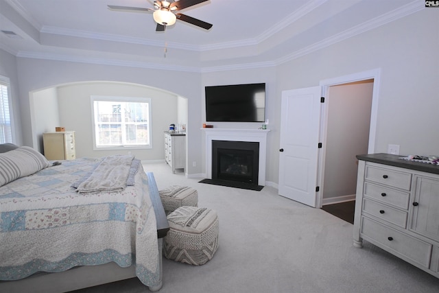 carpeted bedroom with a raised ceiling, crown molding, and ceiling fan