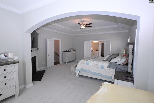 bedroom with crown molding, ceiling fan, ensuite bathroom, light carpet, and a raised ceiling