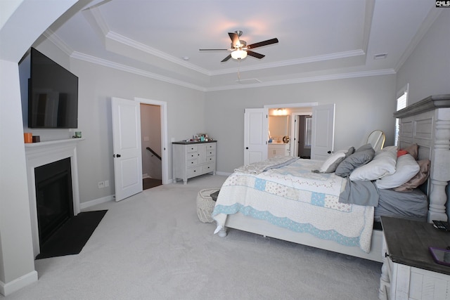 carpeted bedroom with connected bathroom, crown molding, a raised ceiling, and ceiling fan