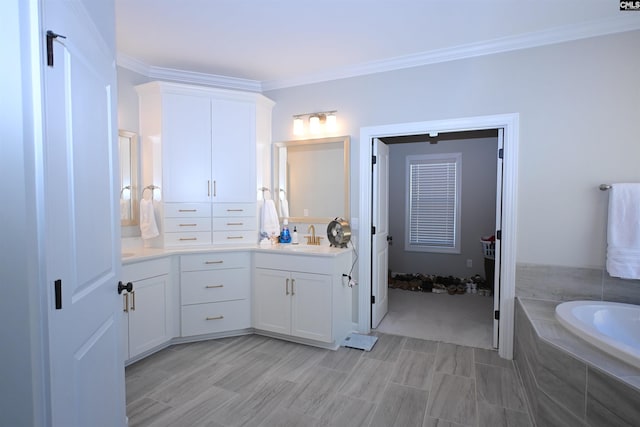 bathroom with tiled tub, vanity, and ornamental molding