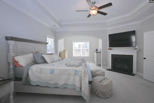 bedroom featuring a raised ceiling, ornamental molding, light colored carpet, and ceiling fan